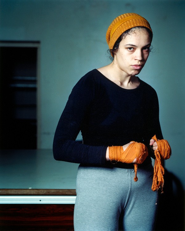 Portrait of a young female boxer standing in a gym.
